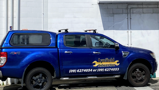 A bright blue pickup truck with branding and phone numbers on its side, parked in front of a white building.