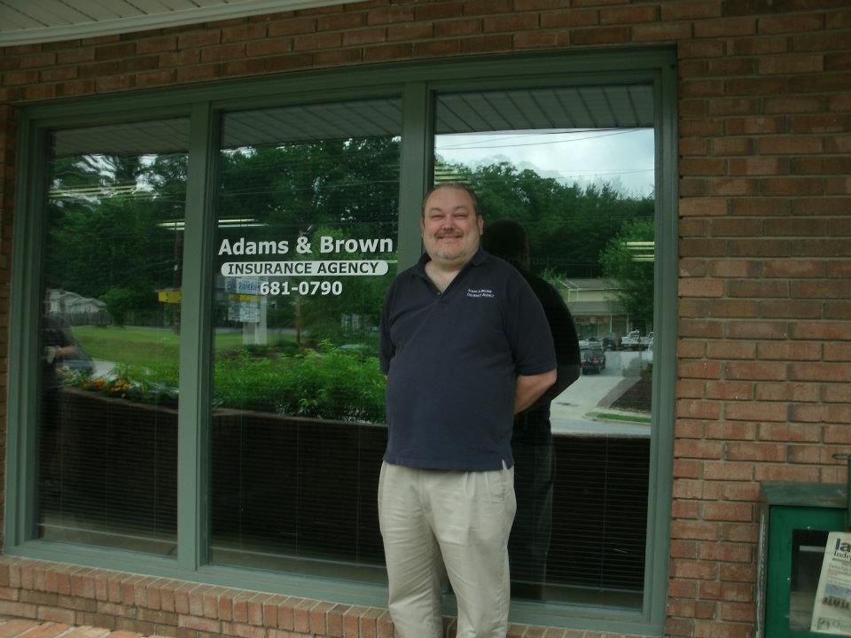 A man standing in front of a adams & brown insurance agency