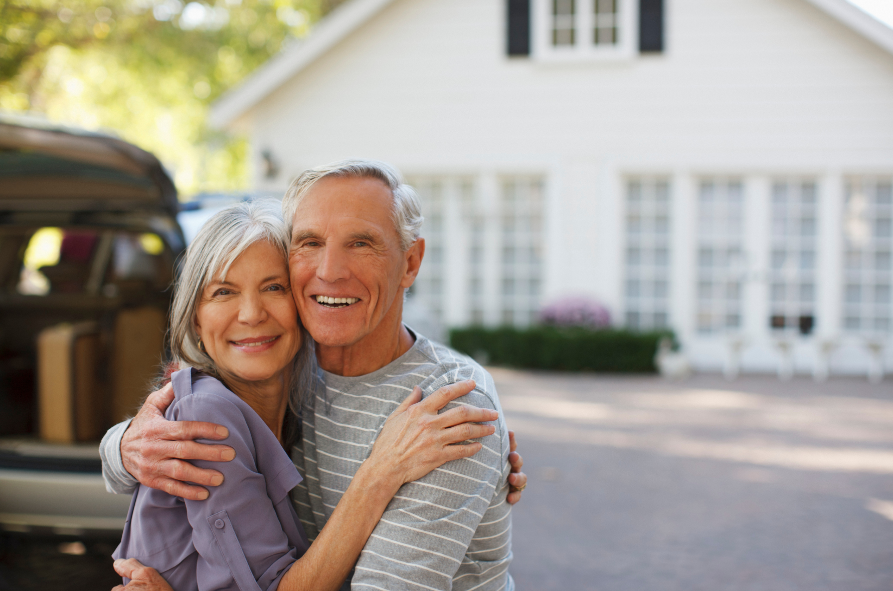 A man is hugging a woman in front of a house.