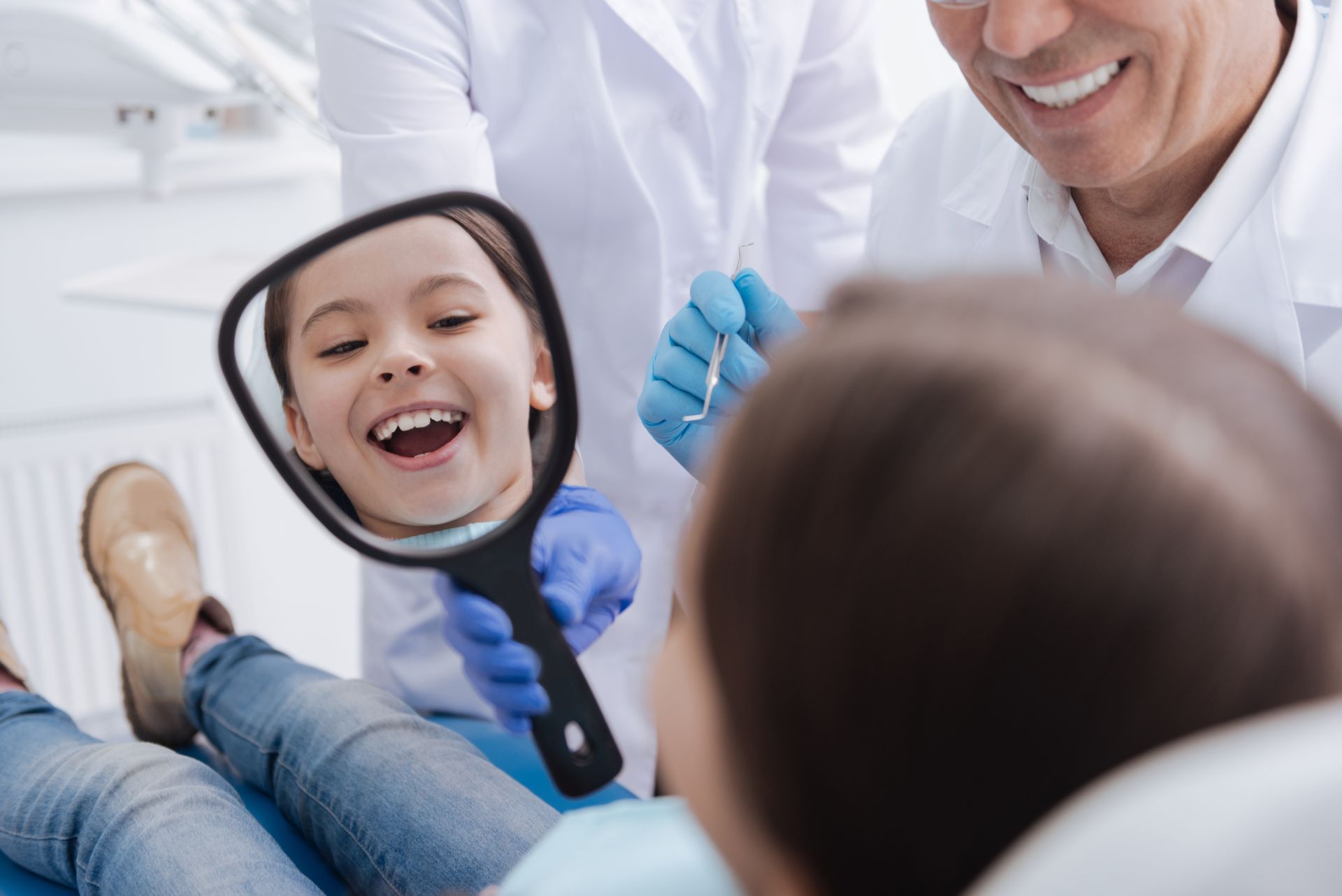 A happy little patient watching herself in the mirror at a family dentist's office.
