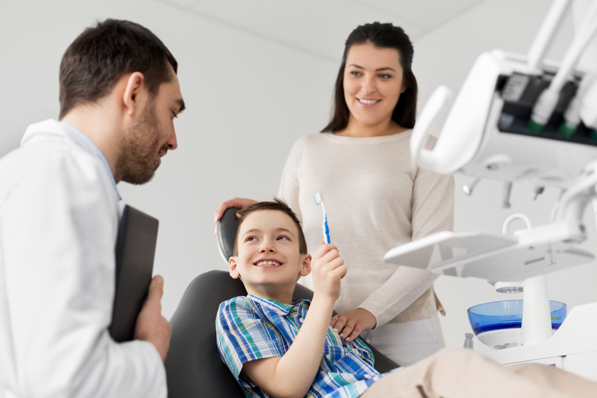 A mother and a son with a toothbrush are visiting a dentist at the dental clinic.