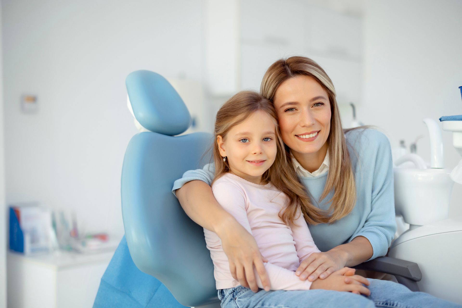 A little girl and her mother are at the dentist's office, showcasing family dental services.