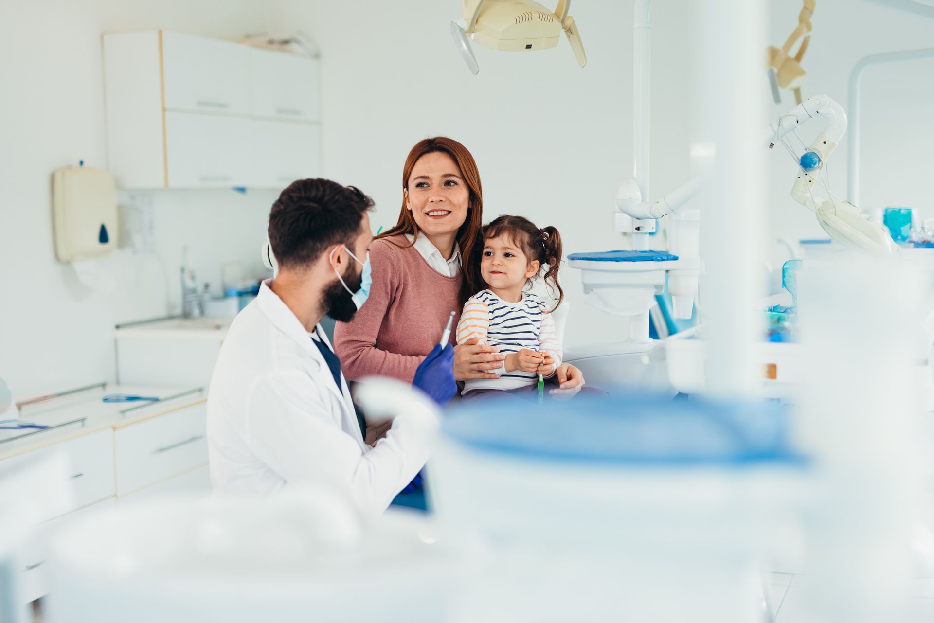 Dentist talking with mother and daughter in dental office. Dentist talking with mother and daughter in dental office.