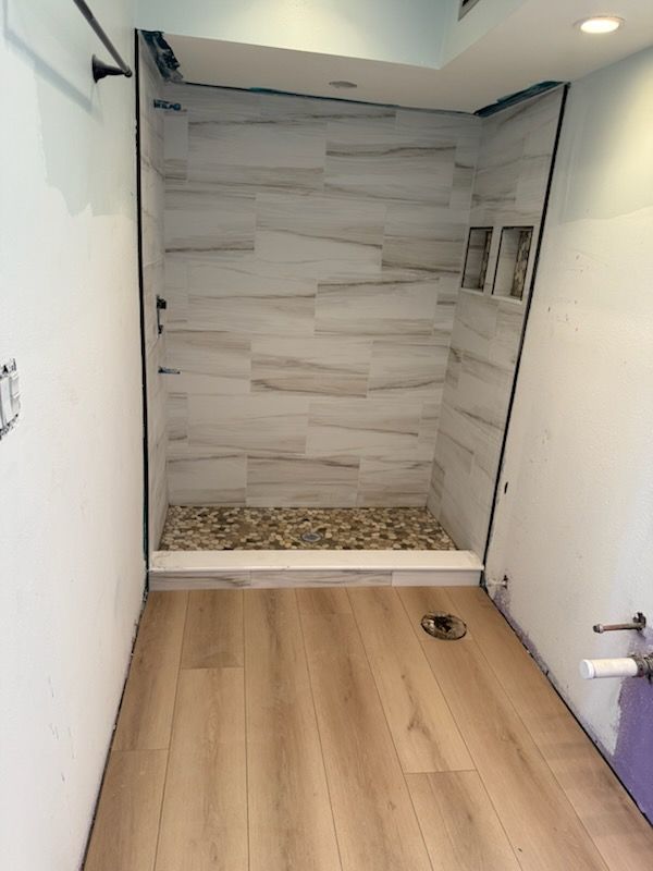 A bathroom with a walk in shower and wooden floors