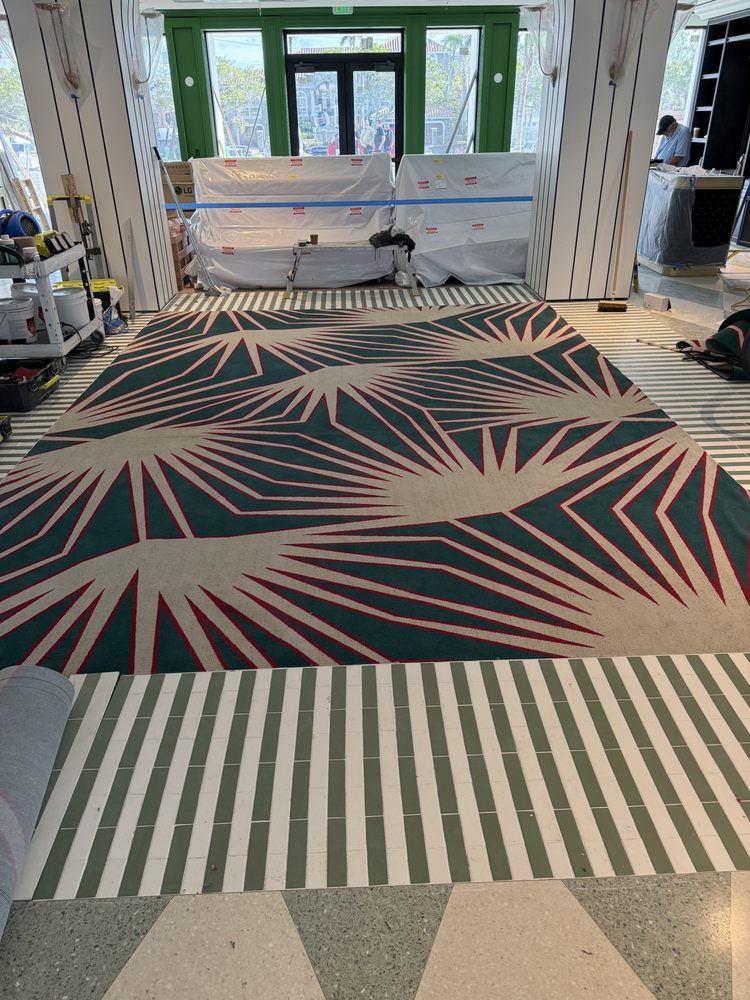 A large rug with a geometric pattern is on the floor of a building.