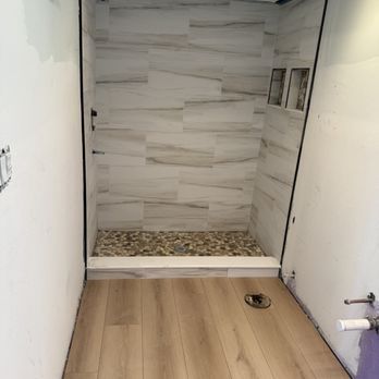A bathroom with a walk in shower and a wooden floor.