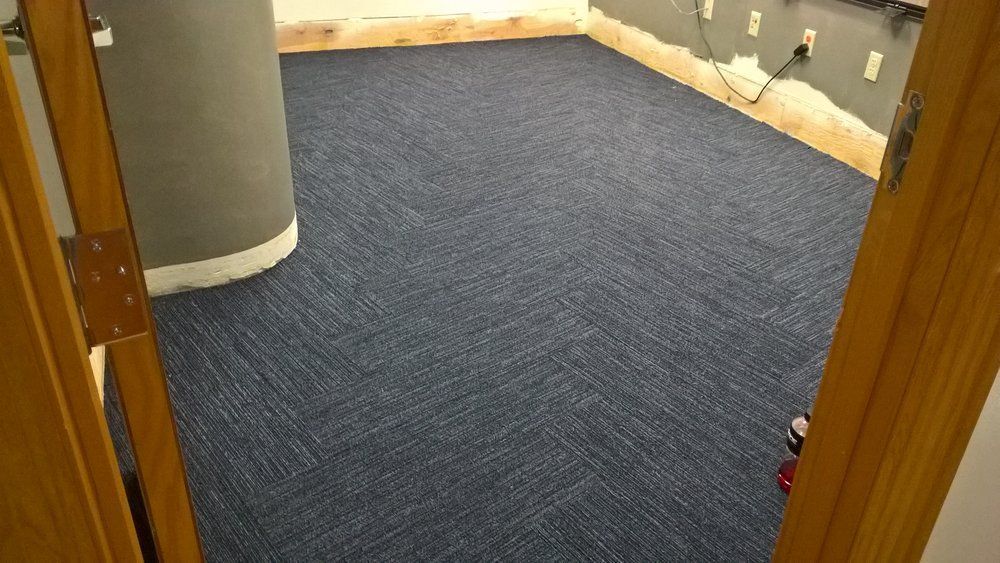 A room with a blue carpeted floor and a wooden door.