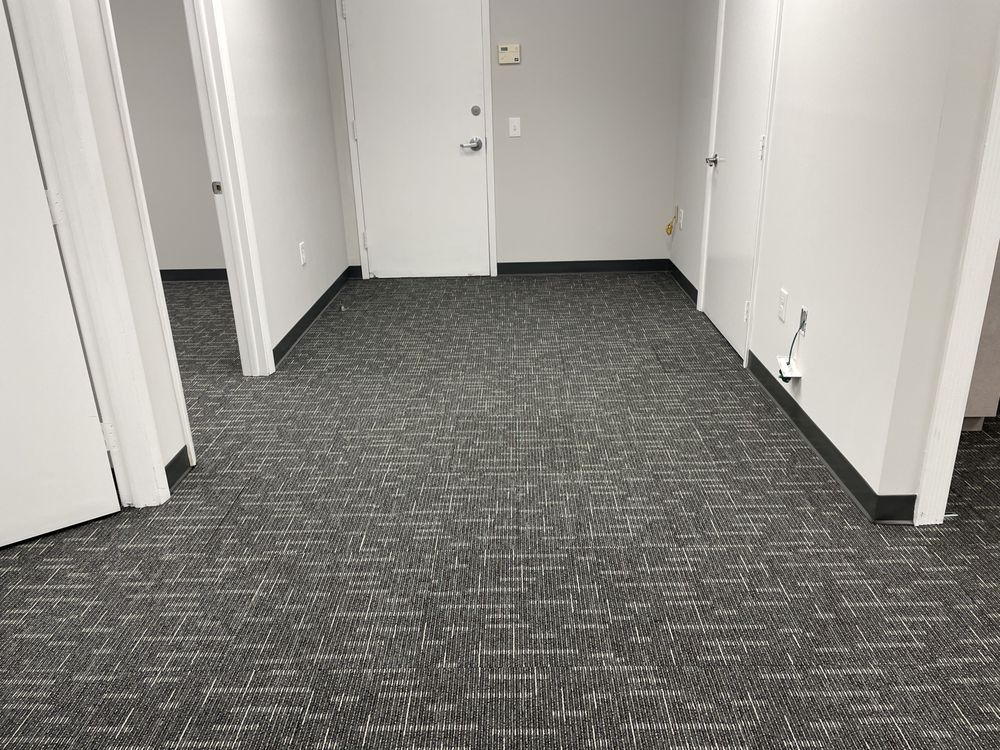 A room with a carpeted floor and two doors.