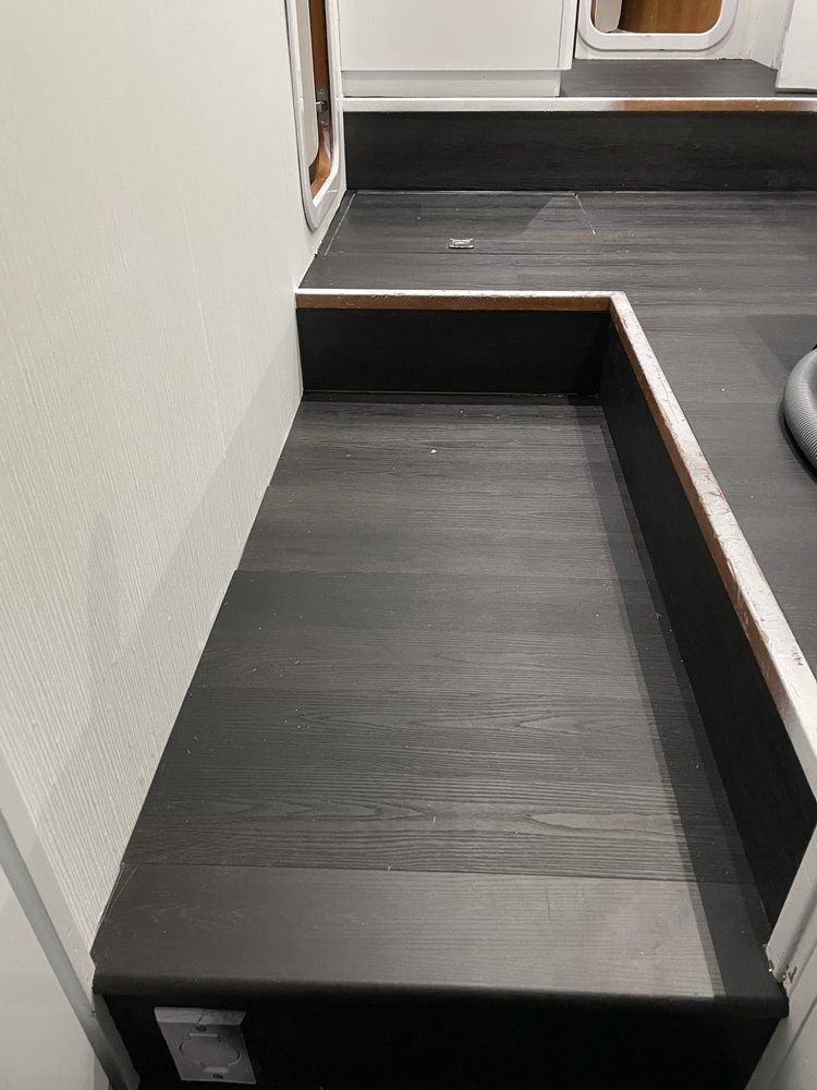 A staircase with a black wooden floor and a white wall.