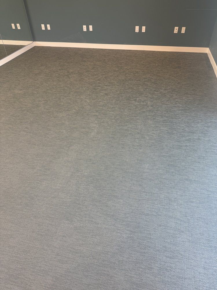 A gray carpeted floor in a room with a blue wall.