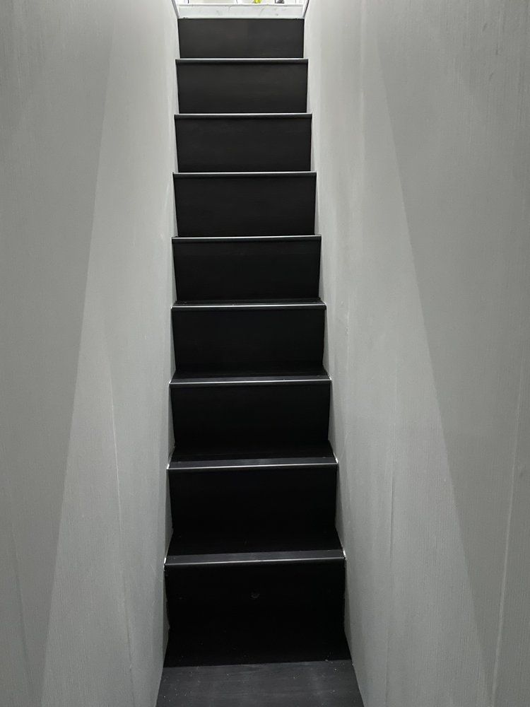 A set of black stairs leading up to a white wall.