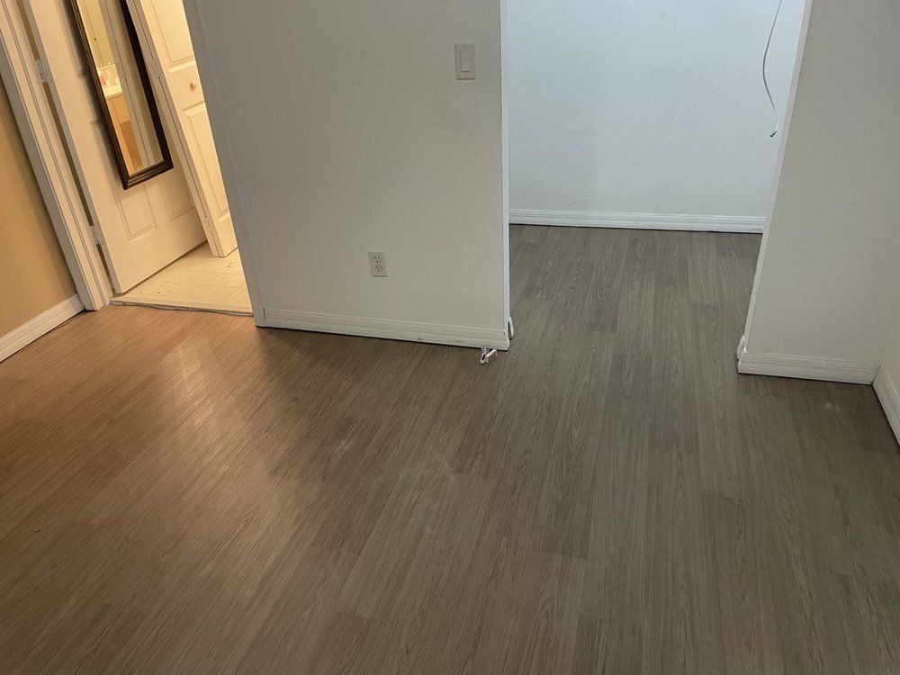 A room with a wooden floor and a door leading to a bathroom.