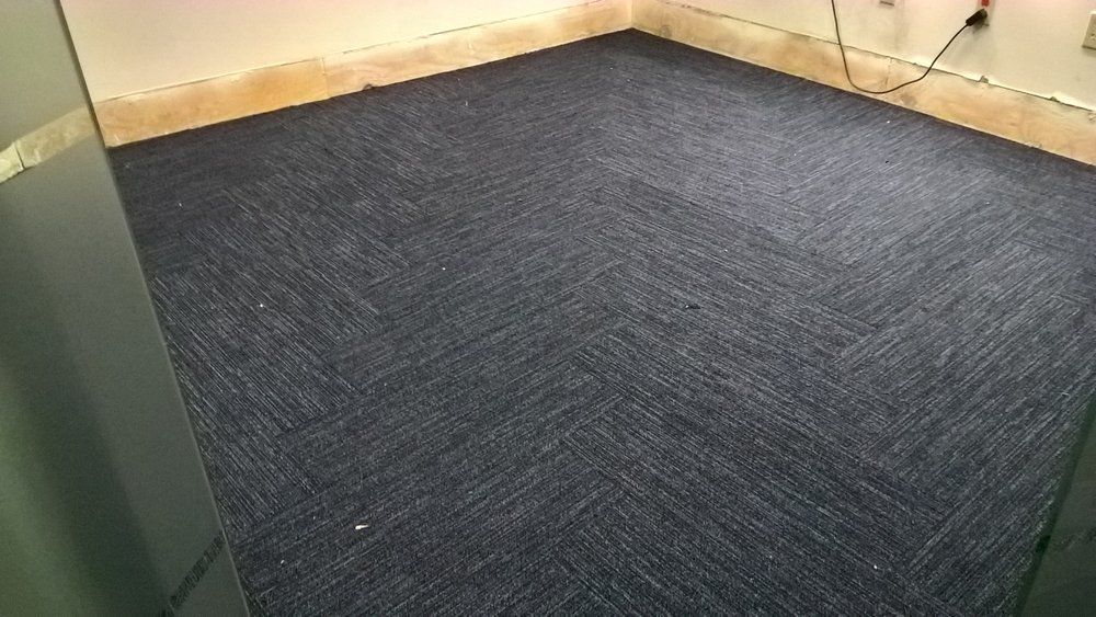 A room with a blue carpeted floor and a white wall.