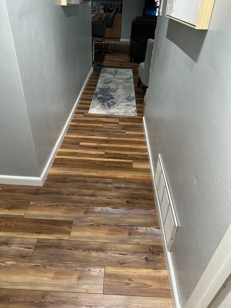 A hallway with hardwood floors and a rug on the floor.