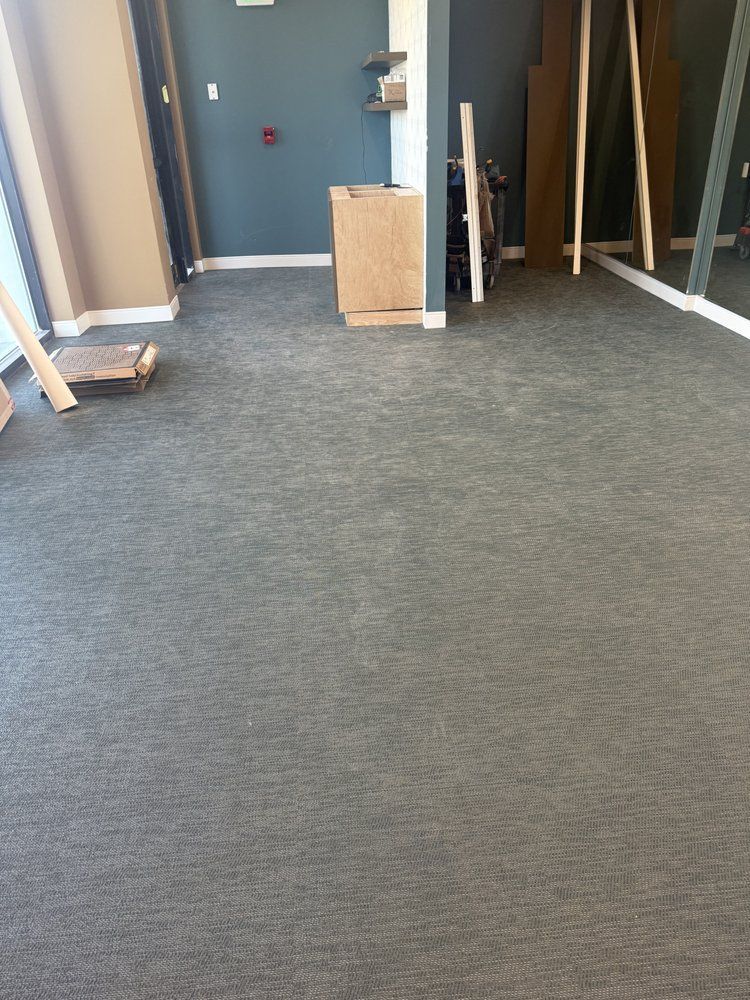 A room with a carpeted floor and a ladder in it.