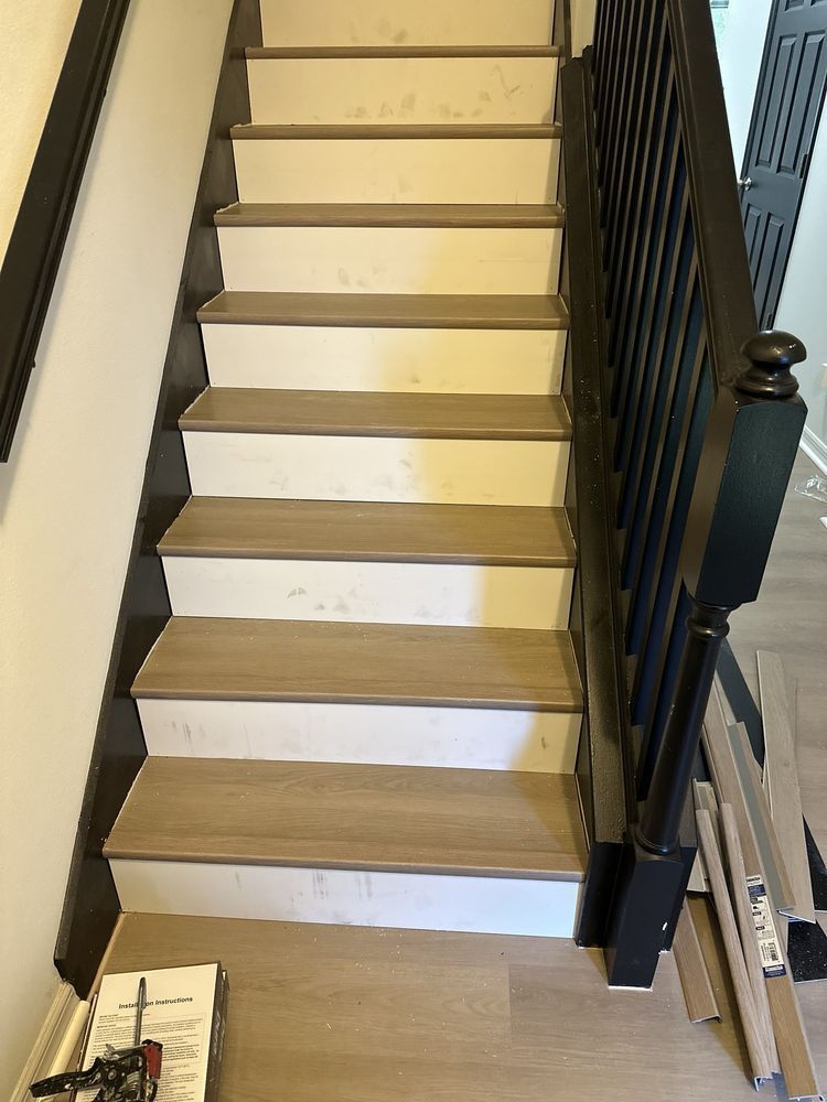 A staircase with white steps and a black railing in a house.