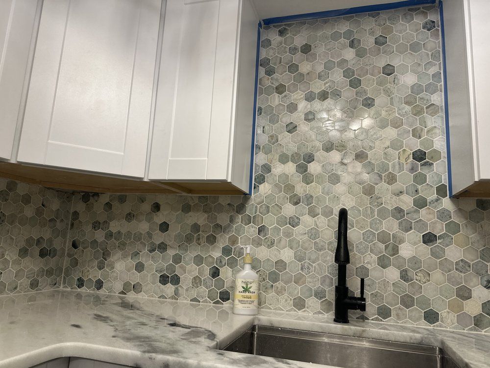 A kitchen with a sink and a soap dispenser on the counter.