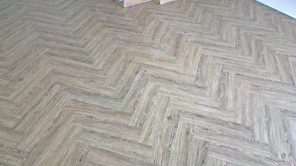 A close up of a wooden floor with a herringbone pattern.