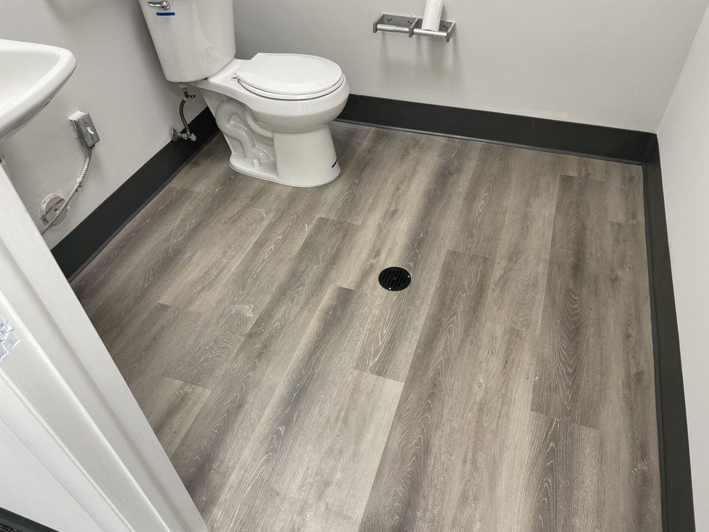 A bathroom with a toilet , sink and wooden floor.