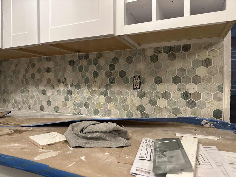 A kitchen is being remodeled and a tile wall is being installed.