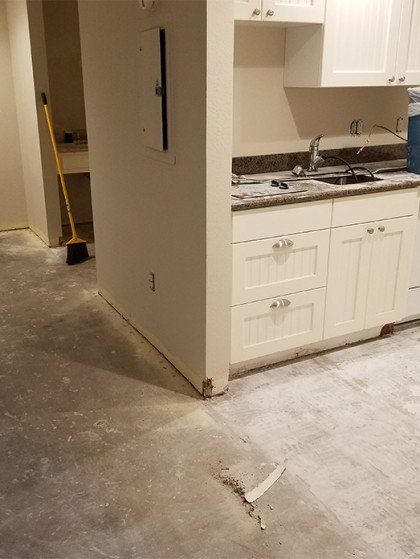 A kitchen with white cabinets and a gray tile floor.