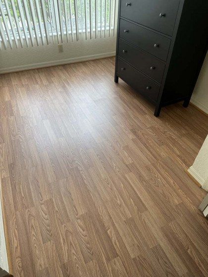 A bedroom with hardwood floors and a black dresser.