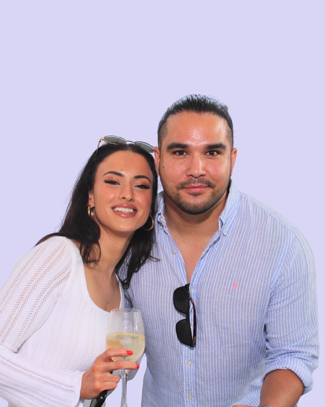 Woman and man smiling, posing together, woman holding wine, light blue background. Versatile group christmas party