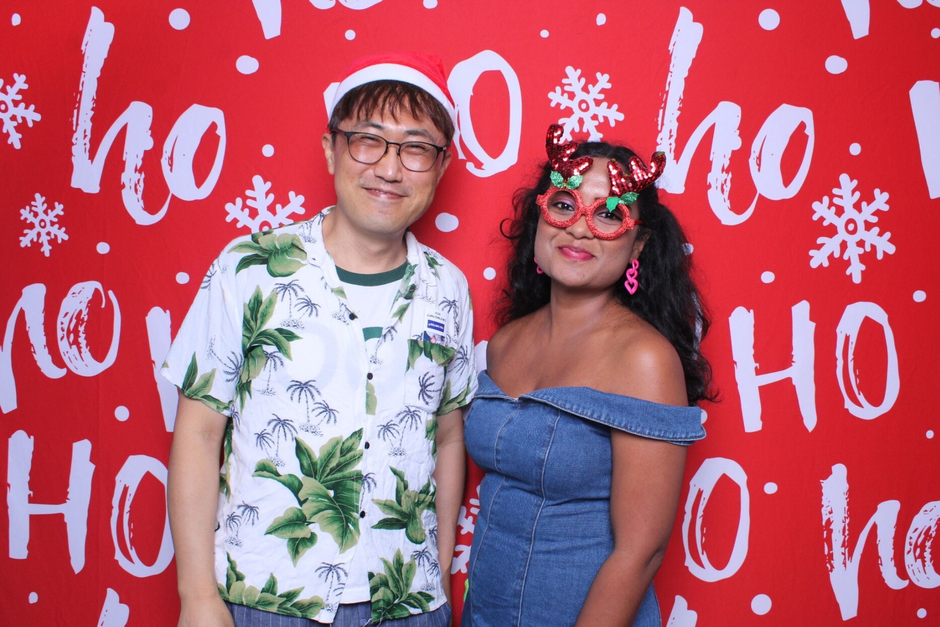 Two people posing in front of a red backdrop with 