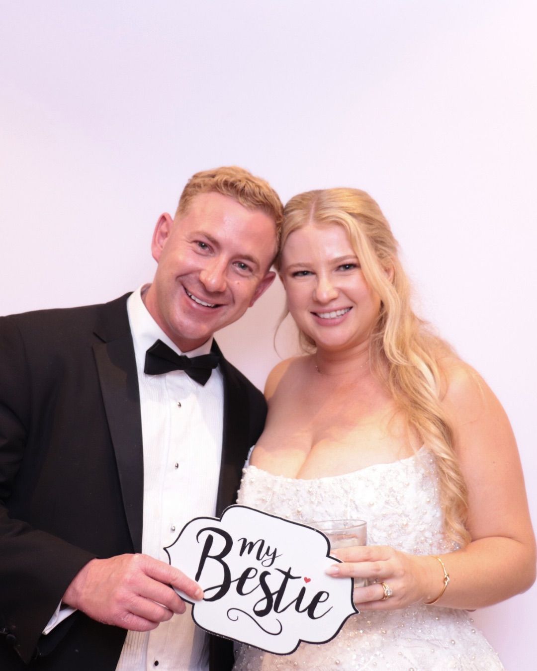 Wedding photo booth. Couple smiling at camera, holding 