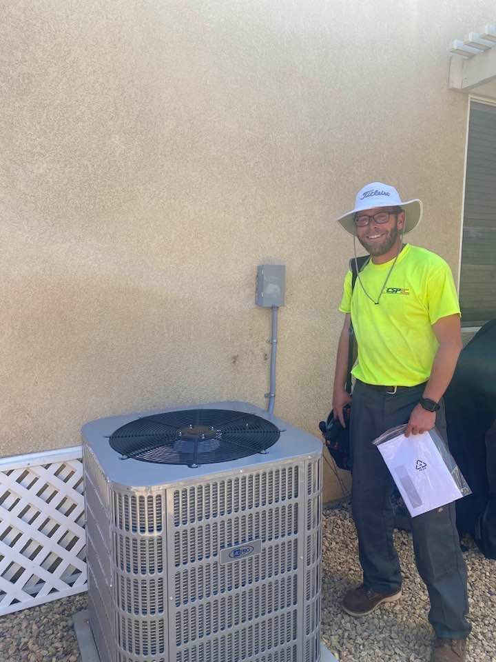 A man in a hat is standing next to a large air conditioner.