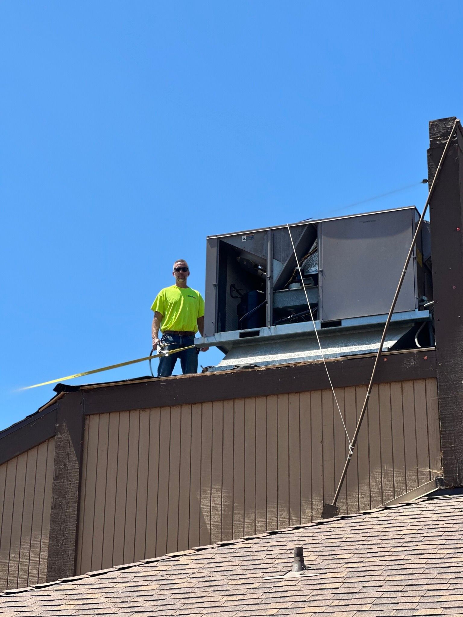 A man is standing on the roof of a building holding a rope.