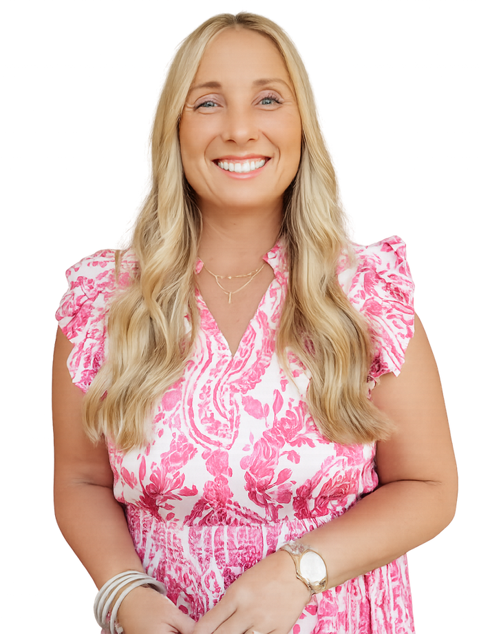 Woman with long blonde hair, smiling, wearing a pink floral dress, standing outdoors.
