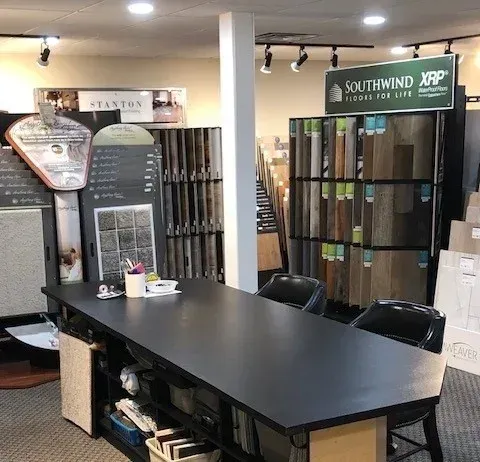 Interior of a flooring showroom with samples, a desk, and two chairs.
