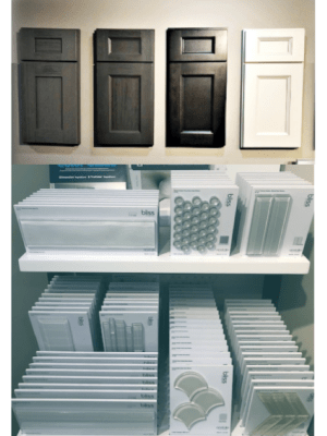 Kitchen cabinet door samples in shades of gray and white, with tile samples on shelves below.