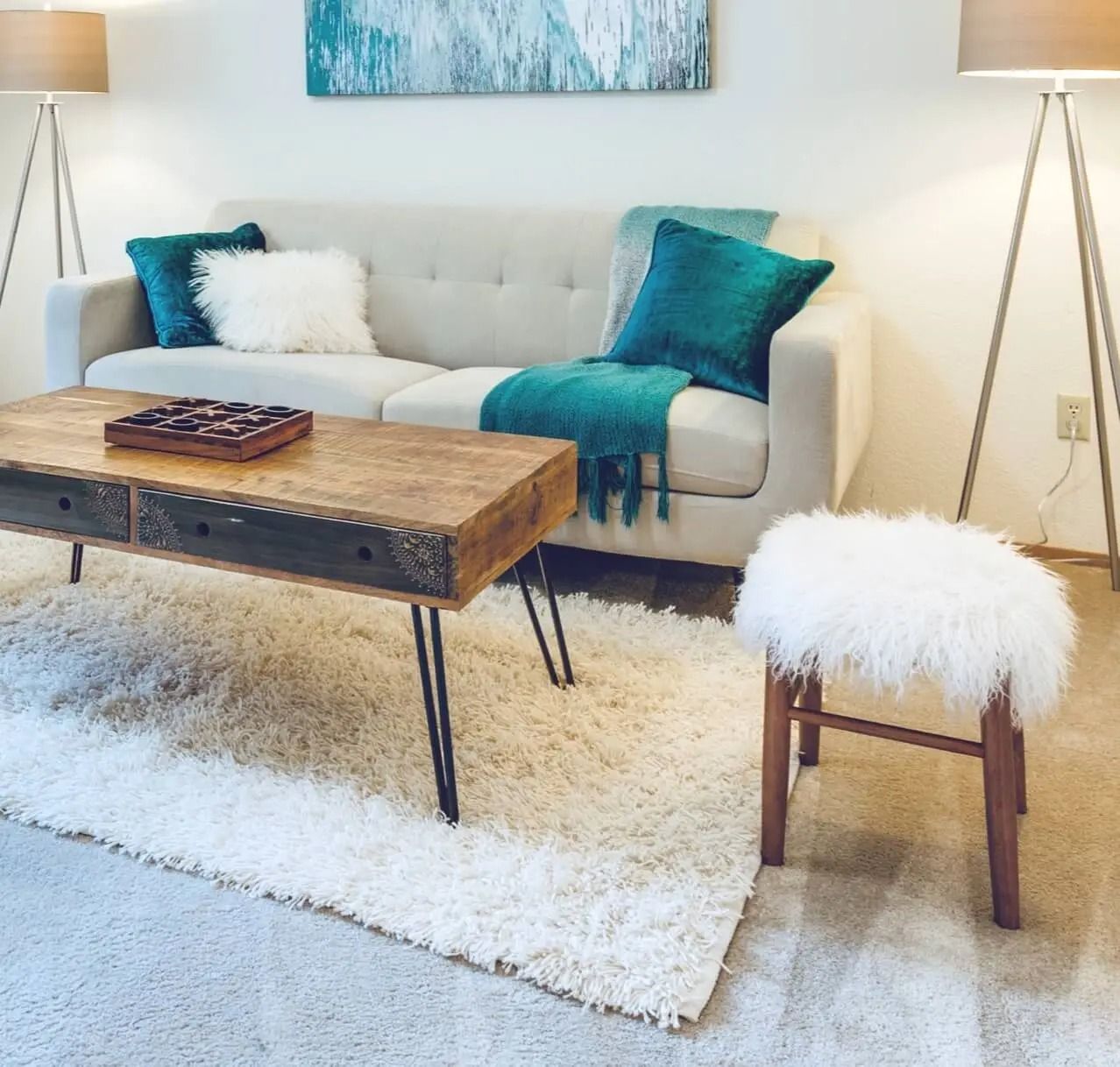 Living room with gray sofa, wooden table, white rug, and teal accents.