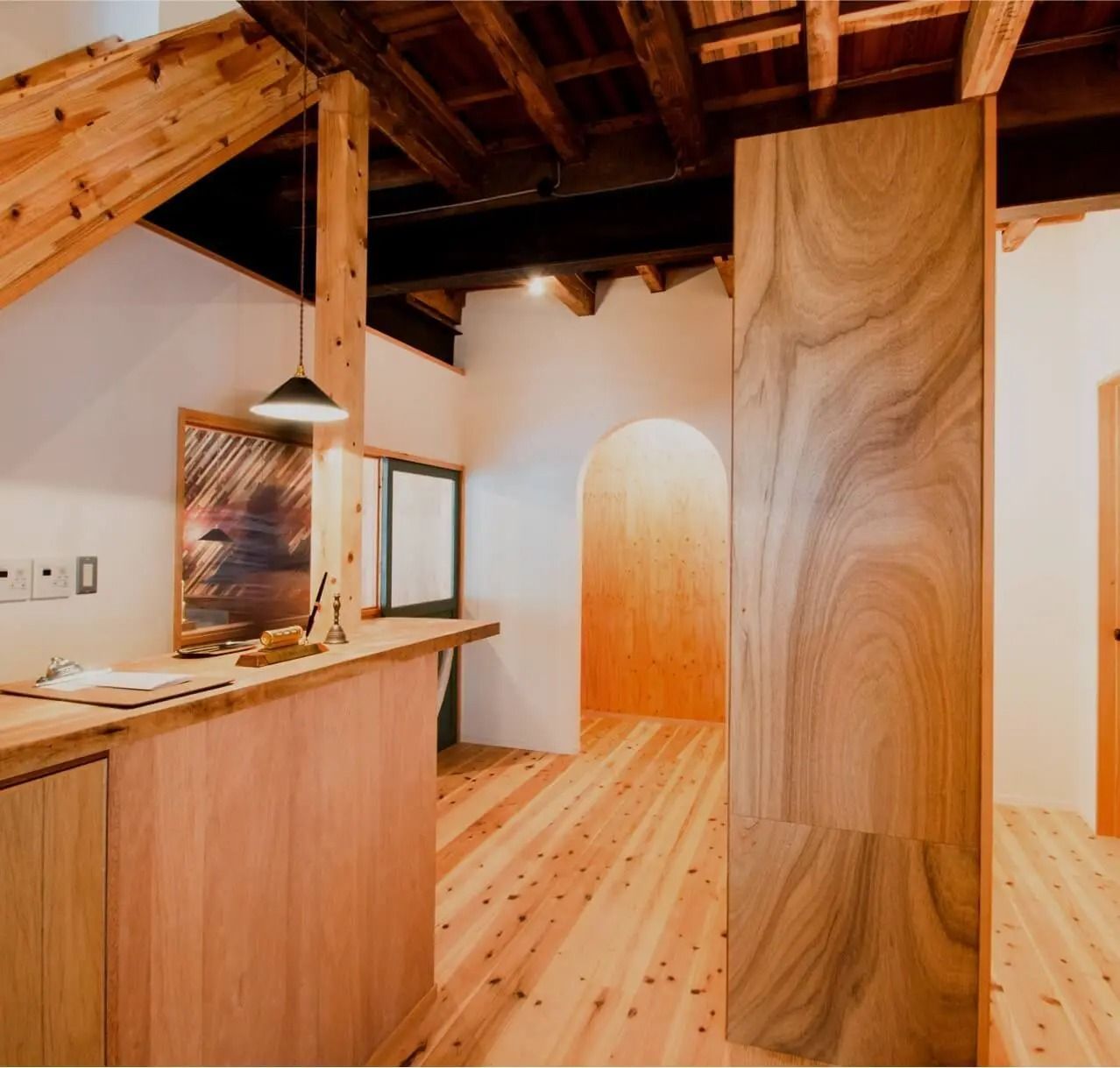 Wooden interior with wood floors, beams, and cabinets; an arched doorway.