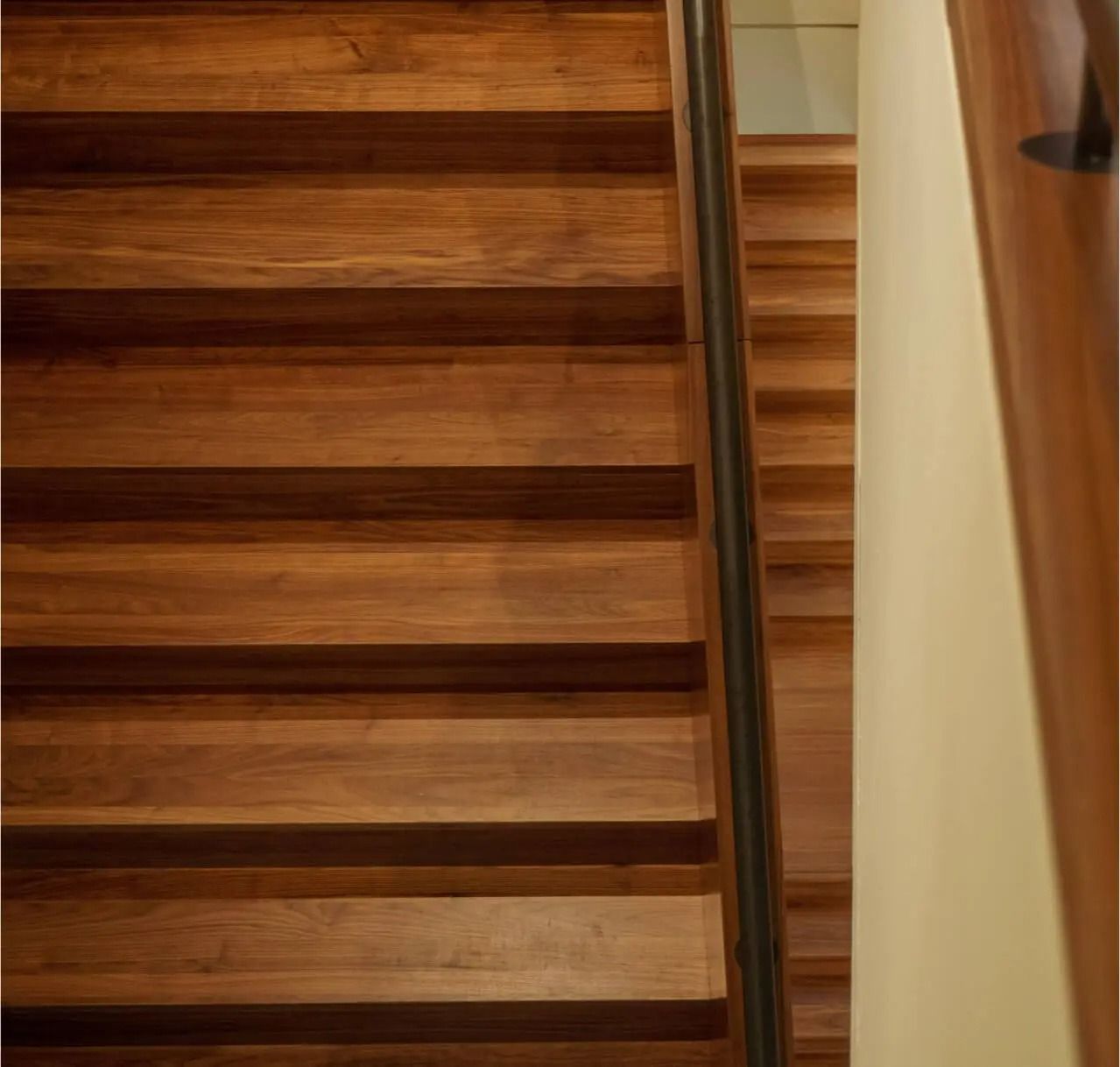 Wooden staircase with a handrail and a light-colored wall.