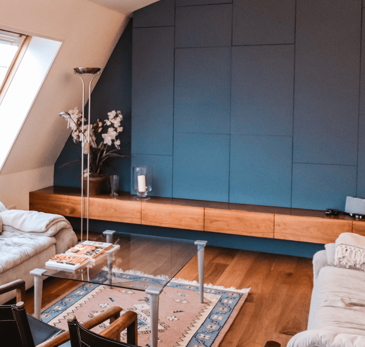 Living room with blue accent wall, wooden floor, and glass coffee table.