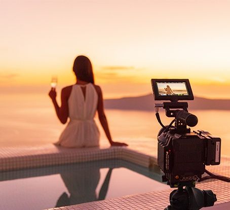 A woman is sitting on the edge of an infinity pool holding a glass of wine