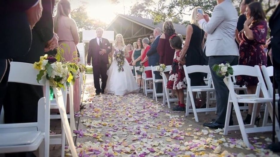 A bride and groom are walking down the aisle at a wedding ceremony