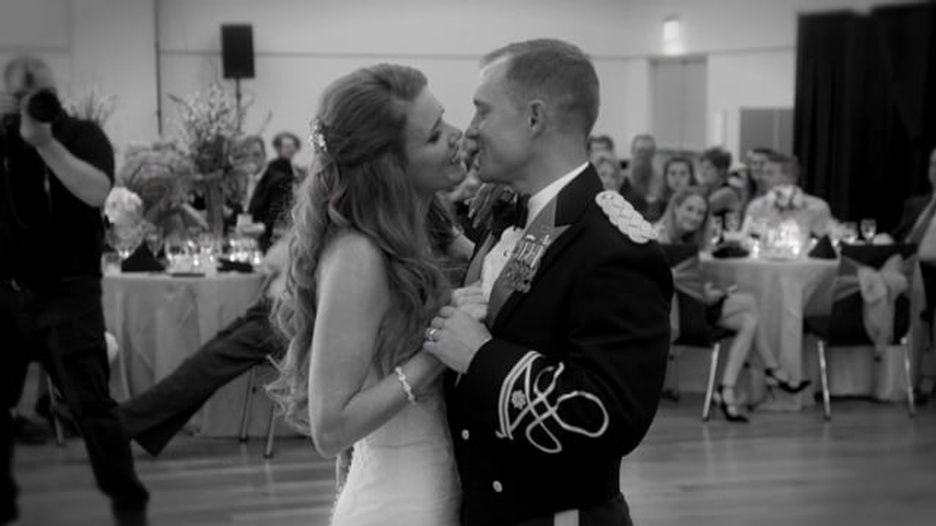 A bride and groom are kissing while dancing at their wedding reception