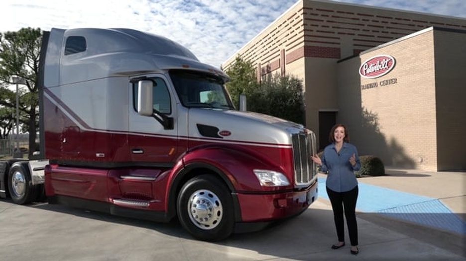 A woman is standing in front of a large semi-truck