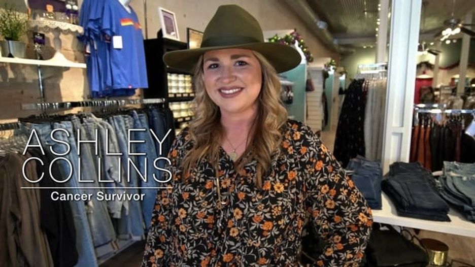 A woman wearing a hat and a floral shirt is standing in a clothing store