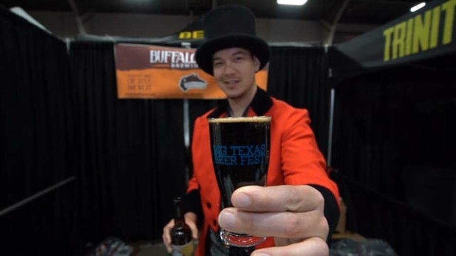 A man in a top hat is holding a glass of beer