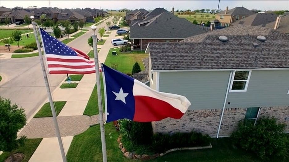 A texas flag is flying in front of a house