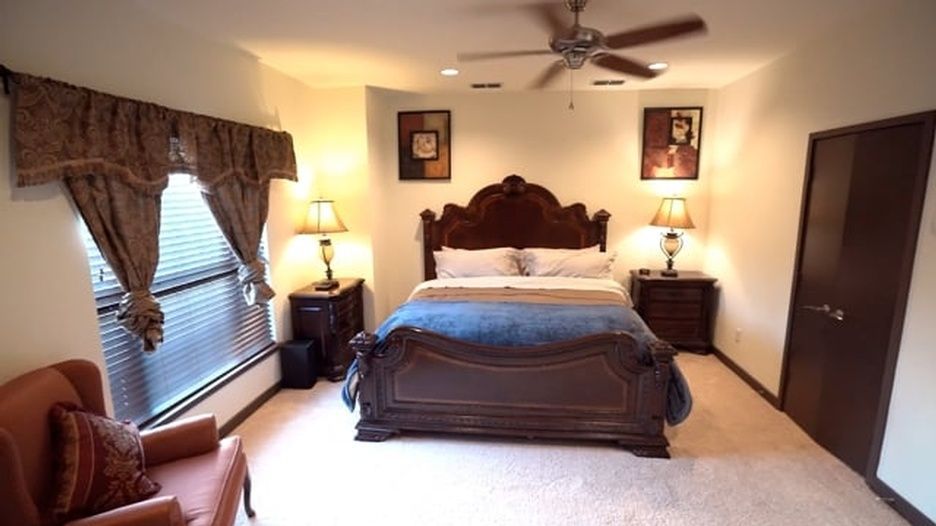 A bedroom with a large bed and a ceiling fan