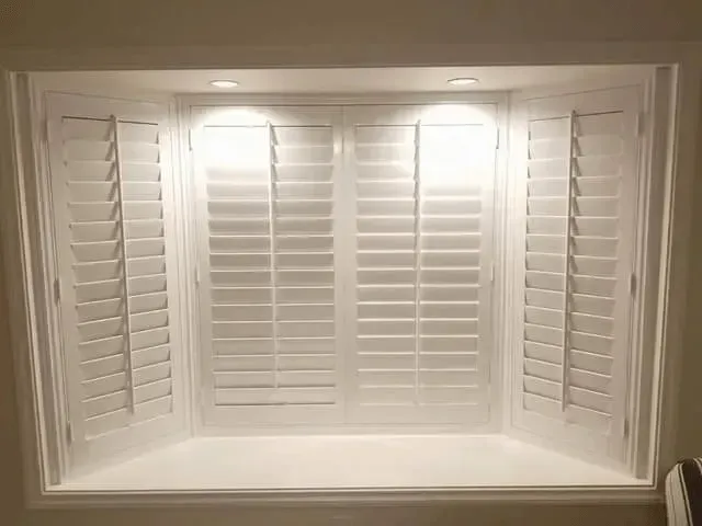 White window shutters in a recessed window, lit from above.