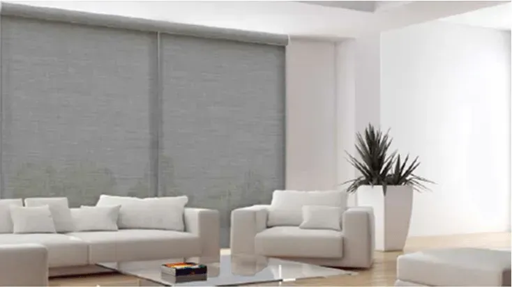 Modern living room with gray roller shades, white furniture, and a potted plant.