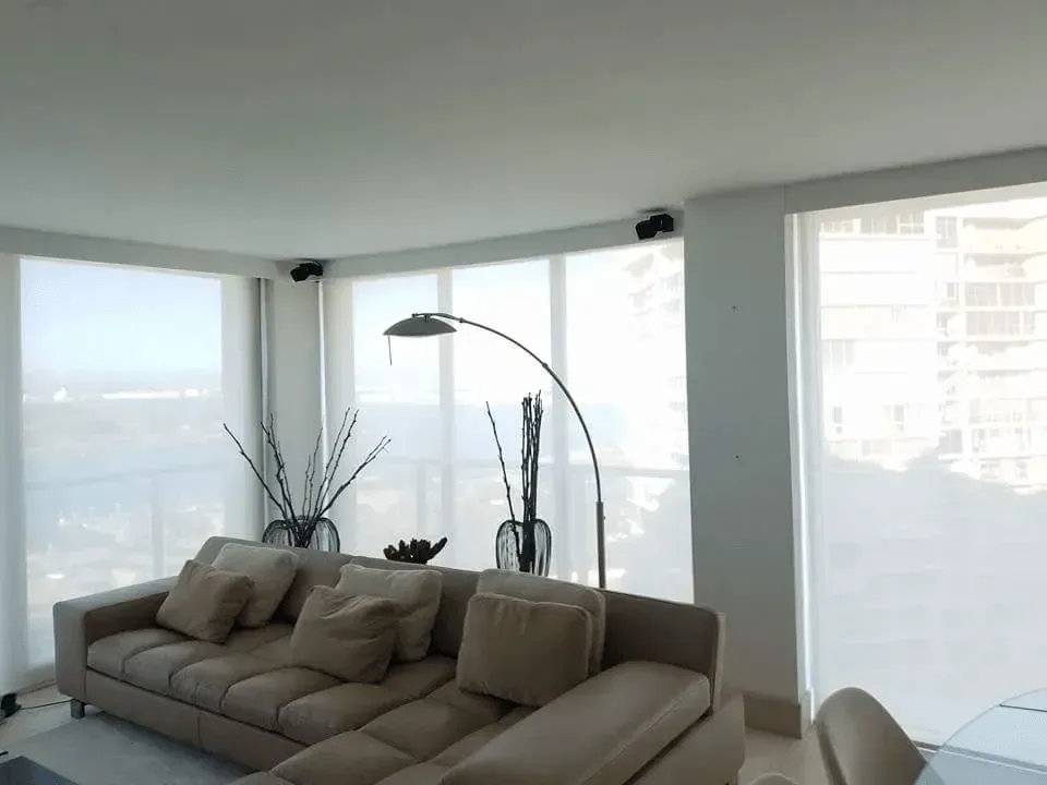 Beige sectional sofa in a bright living room with large windows and a floor lamp.