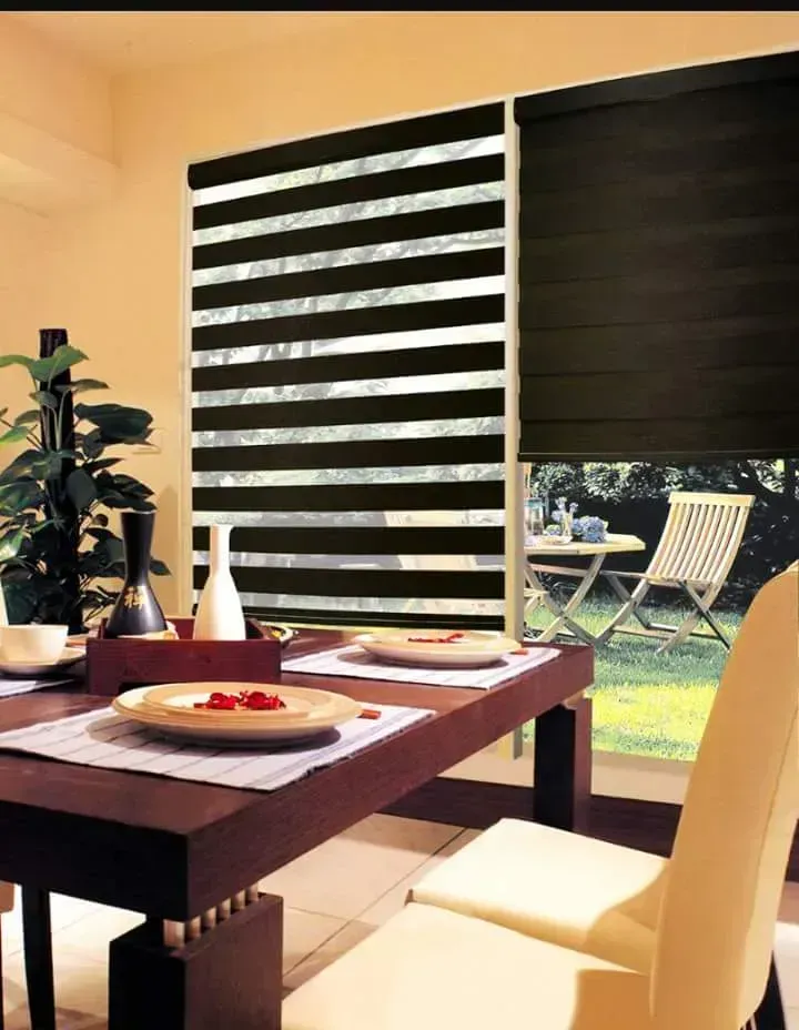 Dining room with striped blinds, table set for two, and a view of a patio.